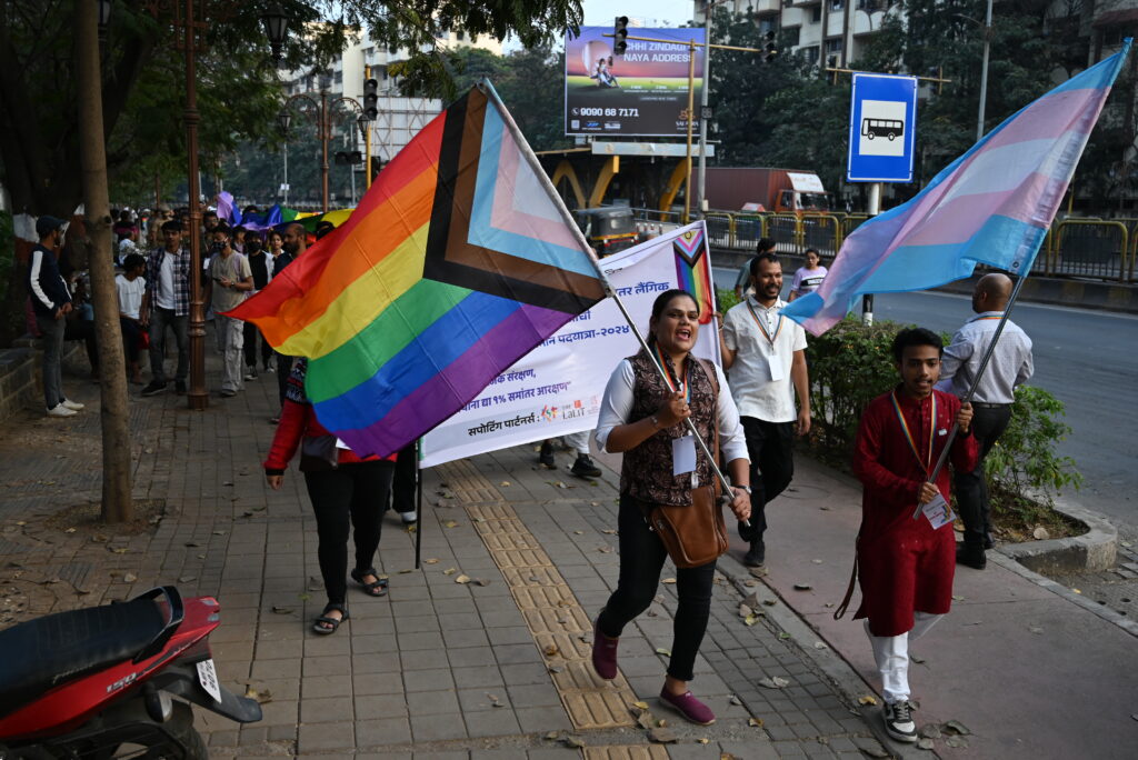 Grand marshals holding pride flag & trans flag while leading the pride walk