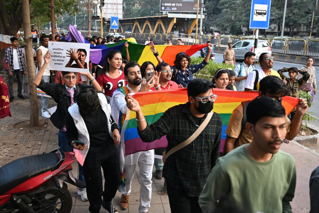 People participating in Pride Walk, with pride flag and posters