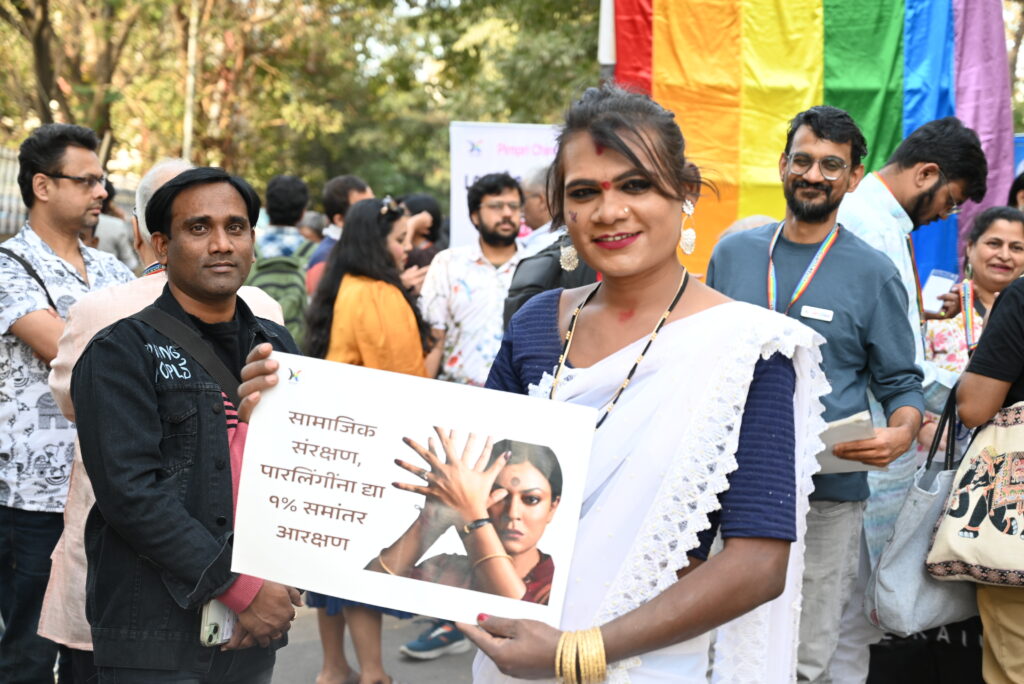 Transwoman participating in Pride Walk, holding a placard that asks for horizontal reservation for transgender community