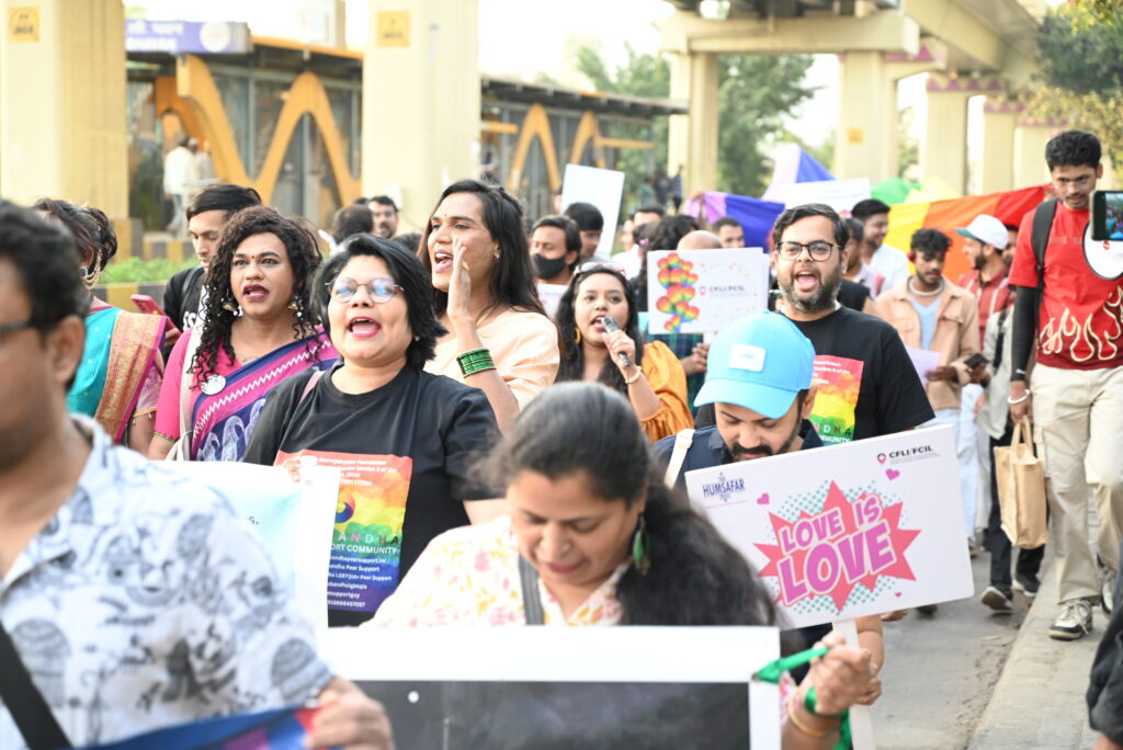 People participating in pride walk, raising slogans, holding placards like "Love is love"
